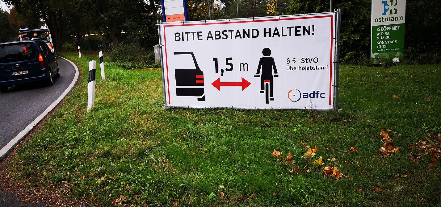 Plakate an Straßenrand weisen auf Abstandhalten hin