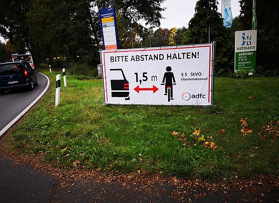 Plakate an Straßenrand weisen auf Abstandhalten hin